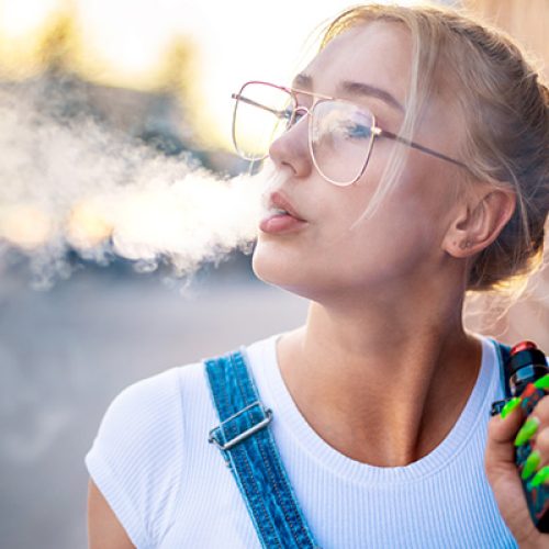 A blonde girl smoking a vape.