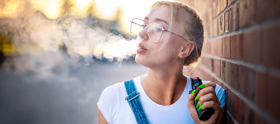 A blonde girl smoking a vape.